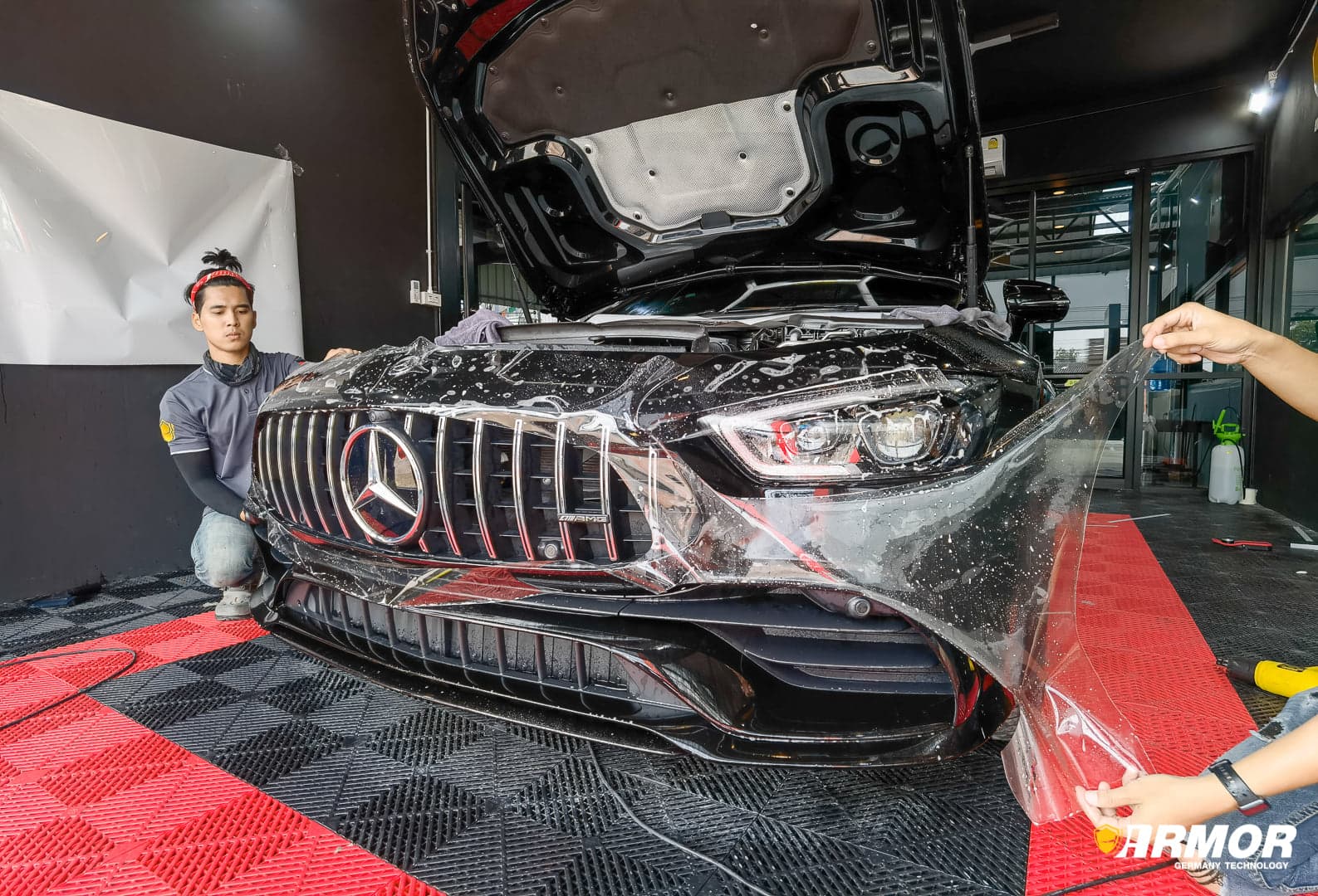 ทีมงานกำลังติดตั้งฟิล์มใสกันรอย PPF ที่กันชนหน้าของรถ Mercedes-Benz อย่างพิถีพิถัน